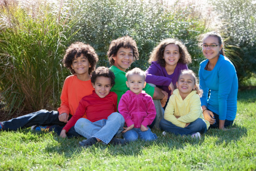 A full length image of a group of mixed race children (caucasian and African American) from a large family. Ages range from 2 to 16. Shallow DOF