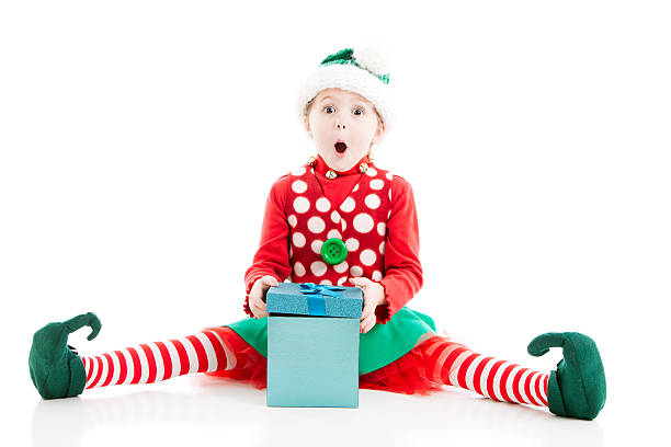 Santas Elf is Surprised Opening Christmas Present A little girl, dressed as one of Santas Christmas elves, is surprised and excited opening Christmas present. elf sitting stock pictures, royalty-free photos & images