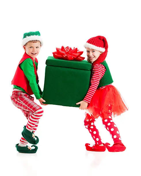 Two young elves struggle carrying a big, heavy, wrapped present.