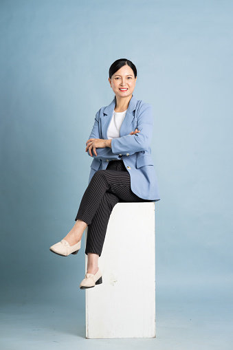 portrait of middle aged asian businesswoman posing on blue background