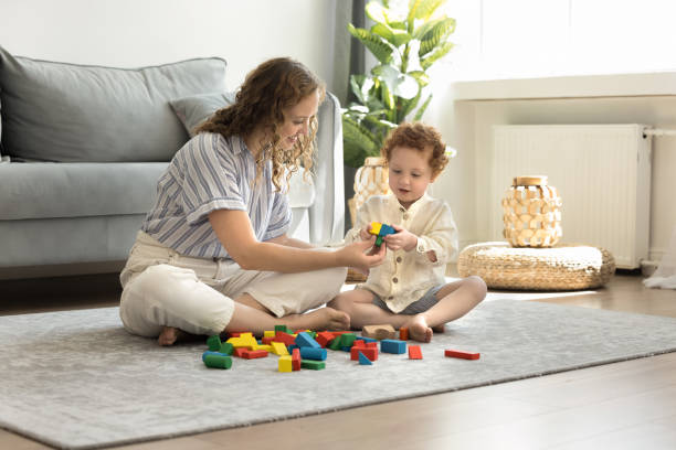 istock Positive caring young mom and cute kid playing toy blocks 1611702235