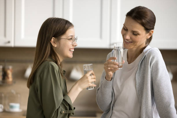 maman heureuse et adolescente positive buvant de l’eau pure - adoption early teens teenager family photos et images de collection