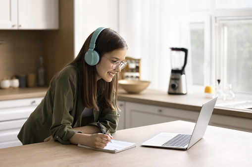 Positive teenager school kid talking on video conference call with classmates, teacher on laptop, attending distant class, lesson, training course, watching lecture, studying at home