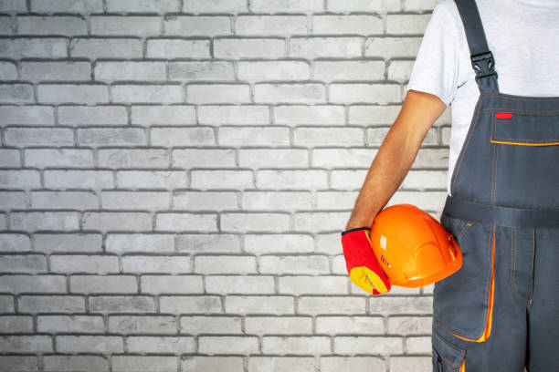 istock Builder in building uniform holding a hard hat. place for text. 1611706713