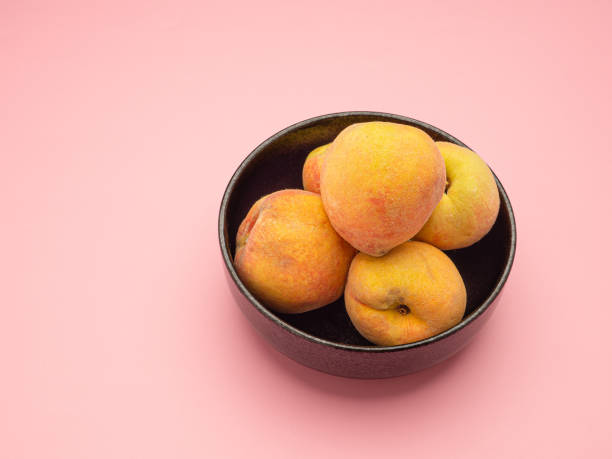 ピンクの背景に新鮮な桃の実をボウルに - fruit vegetable fruit bowl peaches ストックフォトと画像