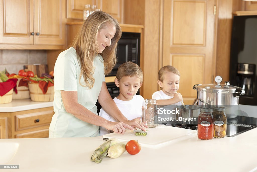Canning: Mother Sons Preserving Homegrown Fruits and Vegetables A waist up image of a caucasian mother and her two sons canning homegrown fruits and vegetables. Family with Two Children Stock Photo