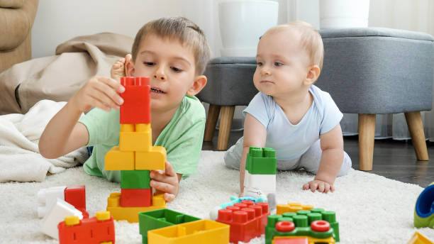 istock Boy teaching his baby brother playing toys and building constructions from bricks and blocks 1611768339