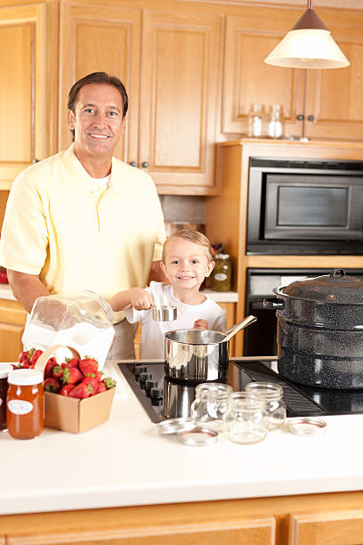 canning: pai e filho fazendo caseiros, compotas de frutas e vegetais cultivadas no local usando - jar canning food preserves - fotografias e filmes do acervo