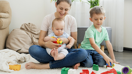 Happy smiling family with children palying on carpet in living room. Concept of family having time together and children development.