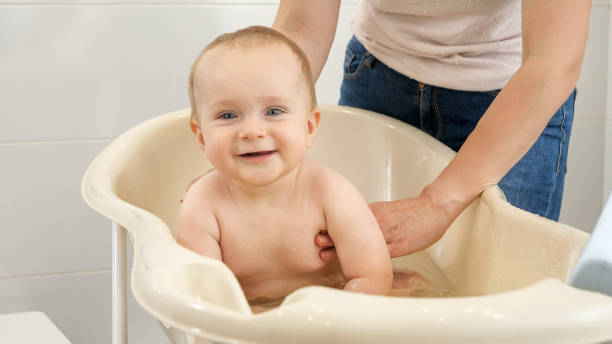 istock Adorable smiling baby boy looking in camera while sitting in bath at bathroom 1611770530