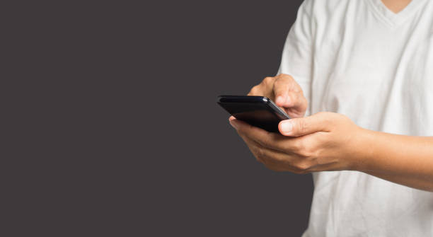istock Close-up of hands using a mobile phone while standing over a gray background 1611775944