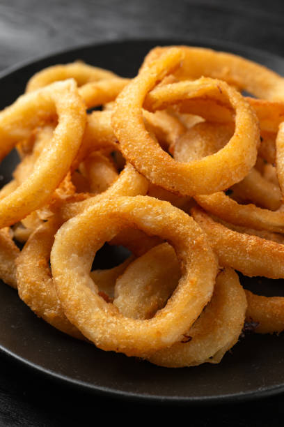 istock Crunchy Fried Battered onion rings on black plate 1611827530