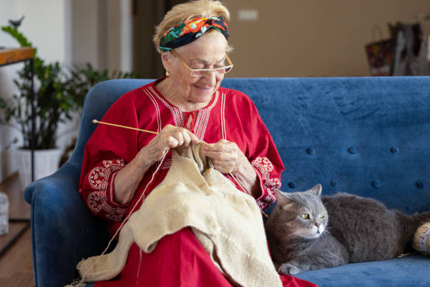 Senior woman knitting on the sofa. stock photo