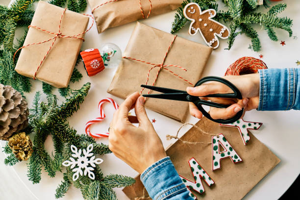 istock Faceless person wrapping Christmas presents on table 1611833869