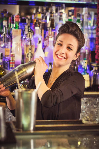 istock Positive female barkeeper shaking cocktail in bar 1611851236