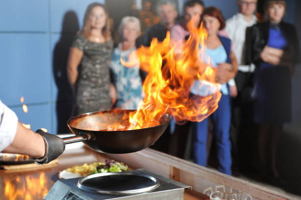 Cooking show for people, chef cooks, fries meat in a frying pan with fire Cooking show for people, chef cooks, fries meat in a frying pan with fire. cooking show stock pictures, royalty-free photos & images