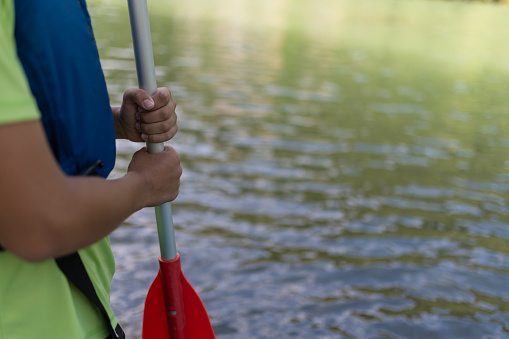 A boy lowers a kayak into the water of the Kolpa River(Slovenia), looks at the water and the banks, takes a selfie, paddles on the green water, above which there are morning mists. Overgrown banks, calm water with rapids. The boy is happy, triumphantly enjoying the river. Happy socializing on holidays and vacations.