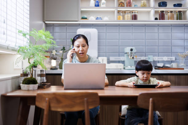 istock Mom makes phone calls while working from home, and child plays games 1611891477