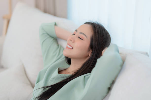 istock Relaxed young asian woman enjoying rest on comfortable sofa at home. 1611891493