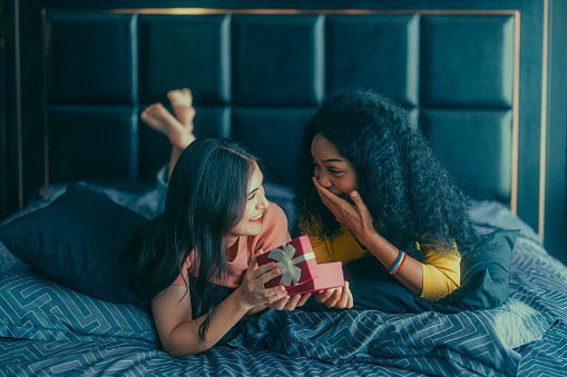 Lesbians share gifts on special and memorable anniversaries. A couple spending quality time to celebrate together A romantic and lovely moment creates feelings of surprise, warmth, and sincerity.