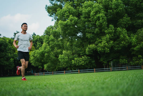 Energetic Asian man running outdoors in nature