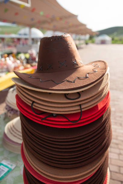 Wooden wall of a barn, with a wood sign hanging on it ready for copy, along with a cowboy hat and boots