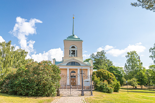 A yellow wooden building in a park on sunny summer day.