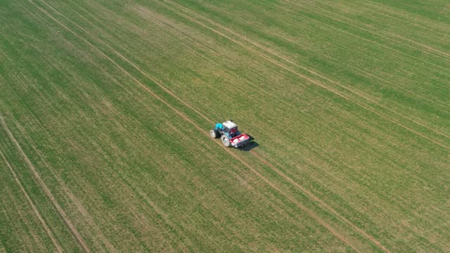 Aerial Flying Above Tractor With Trailer Sprays Chemical Fertilizer Rural Field