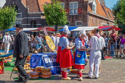 Edam, Netherlands, August 10, 2022; Dutch cheese girls in clogs with braided hair and a trader at the cheese market in Edam.