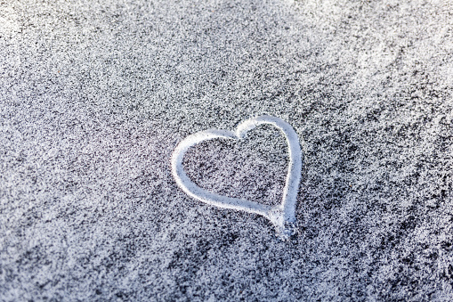 Black soot from the boiler room on white snow. Natural background. Snow mixed with coal soot, poor ecology. Environmental pollution. A heart is painted on the snow. The importance of protecting nature