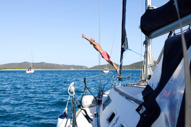 istock Man jumping into the sea from a sailboat, view from the ship 1612082439