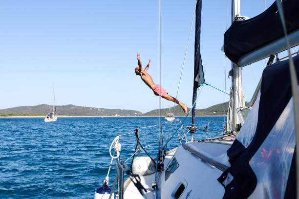 istock Man jumping into the sea from a sailboat, view from the ship 1612082441