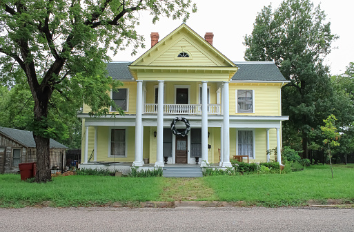 A yellow historic mansion with tall pillars during the summer season near McKinney, Texas