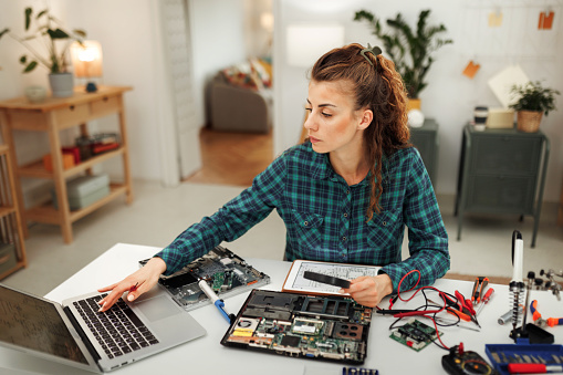 Resourceful female engineer fixes motherboard in her cozy home workspace