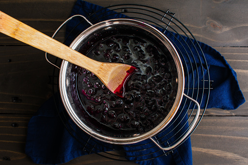 Blueberry compote with a wooden spoon in a saucepan