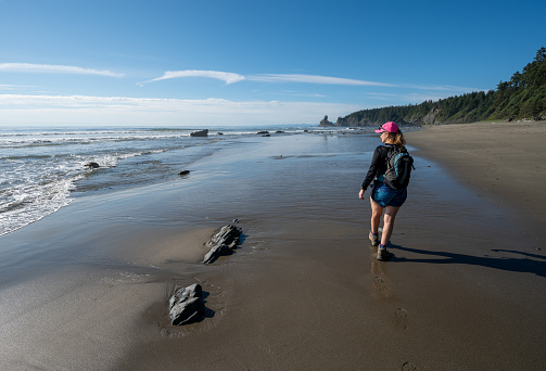 Olympic National Park, Washington - August 1, 2023: Woman hikes on Shi Shi Beach and Trail on sunny summer afternoon.