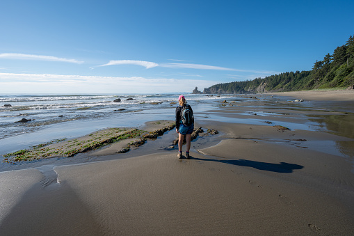 Olympic National Park, Washington - August 1, 2023: Woman hikes on Shi Shi Beach and Trail on sunny summer afternoon.