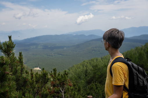 Teenager hiking in the high mountains of Slovenia from Pokljuka to Viševnik, walks up, conquers the top of the mountain, enjoys the views of the forests of Pokljuka, the Julian Alps, enjoys the conquered peak of Viševnik