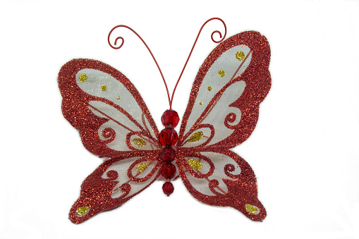 A red butterfly on a white background. Toy on the New Year tree in the form of a butterfly. Decorations decoration red butterfly. Decoration for the New Year tree. New Year's toy set on the Christmas tree