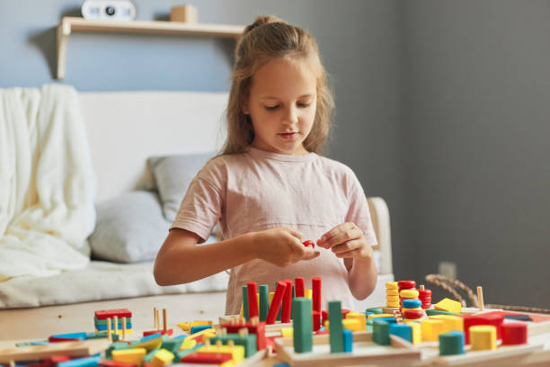 istock Childhood curiosity and discovery. Child's educational playtime. Creating a colorful learning environment. Adorable little girl playing with wooden educational toys at home 1612171843