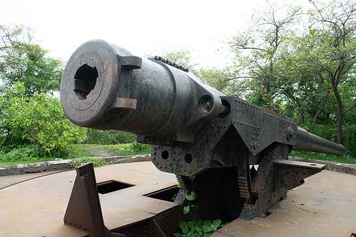 huge nine meter historic cannon on the top most place of cannon hill at elephanta island left by Portuguese during invasion period, navi mumbai, india