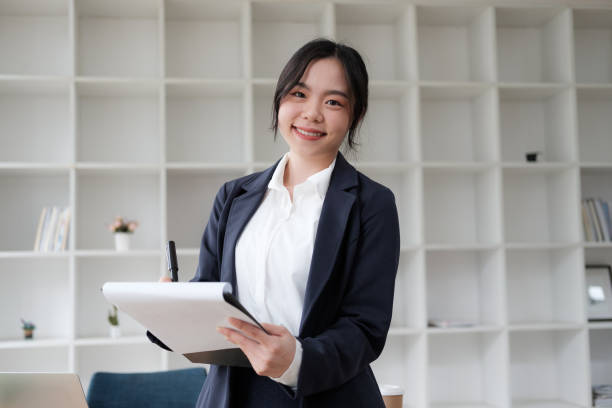 istock Professional Asian businesswoman holding working document while standing in the office room. 1612201324