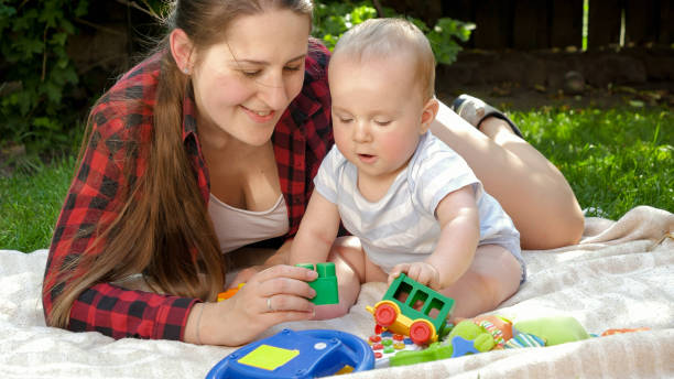 istock Smiling mother with baby boy playing on grass at backyard garden 1612201935