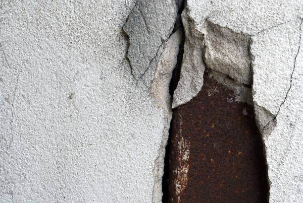 istock A cracked concrete wall with rusty corrugated iron plate for a vintage texture and backgrounds design. 1612225841
