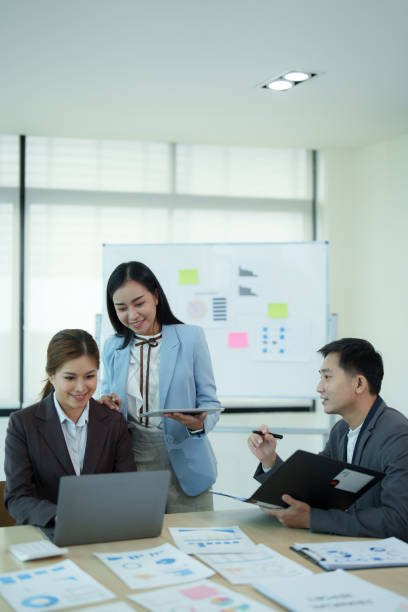 istock Group of diverse businesspeople using a laptop while working together in a modern workspace. 1612261456