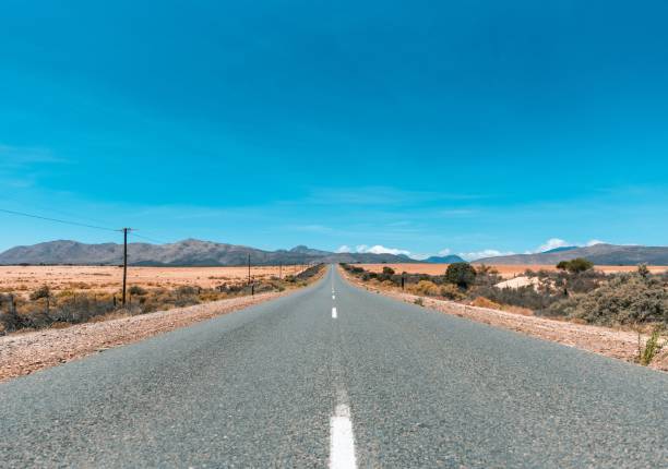 une longue autoroute vide et droite au milieu du désert - featureless photos et images de collection