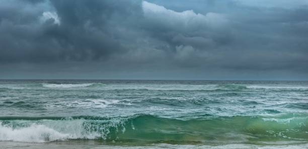 istock Green wave breaking under dark cloudy skies with a storm approaching 1612291089