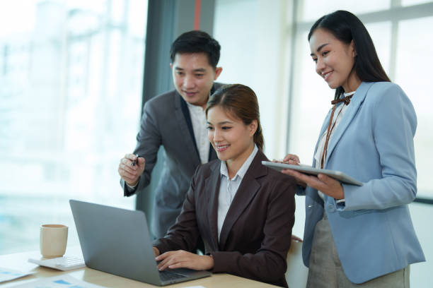 istock Group of diverse businesspeople using a laptop while working together in a modern workspace. 1612315799