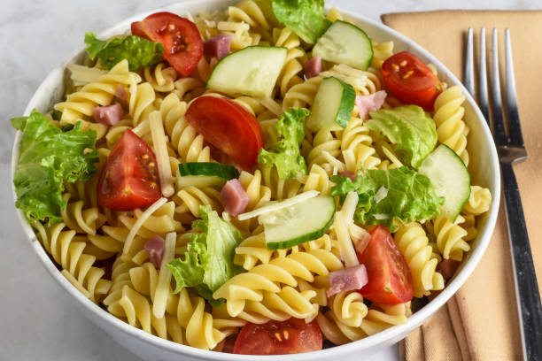 istock rotini pasta salad,  with leetuce tomato and cucumber 1612317872