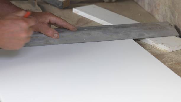 istock Men's hands take measurements and apply cut lines to chipboard. 1612330011